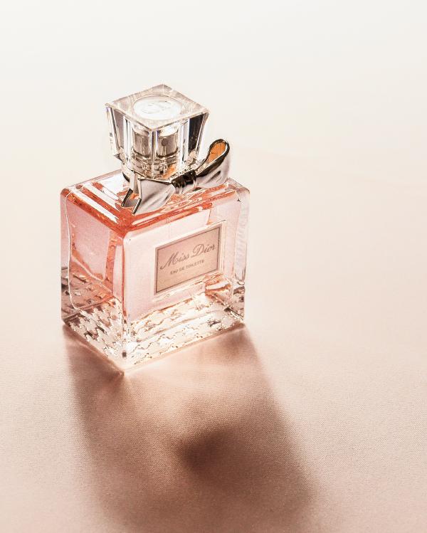 Miss Dior perfume bottle on pink background in diagonal light